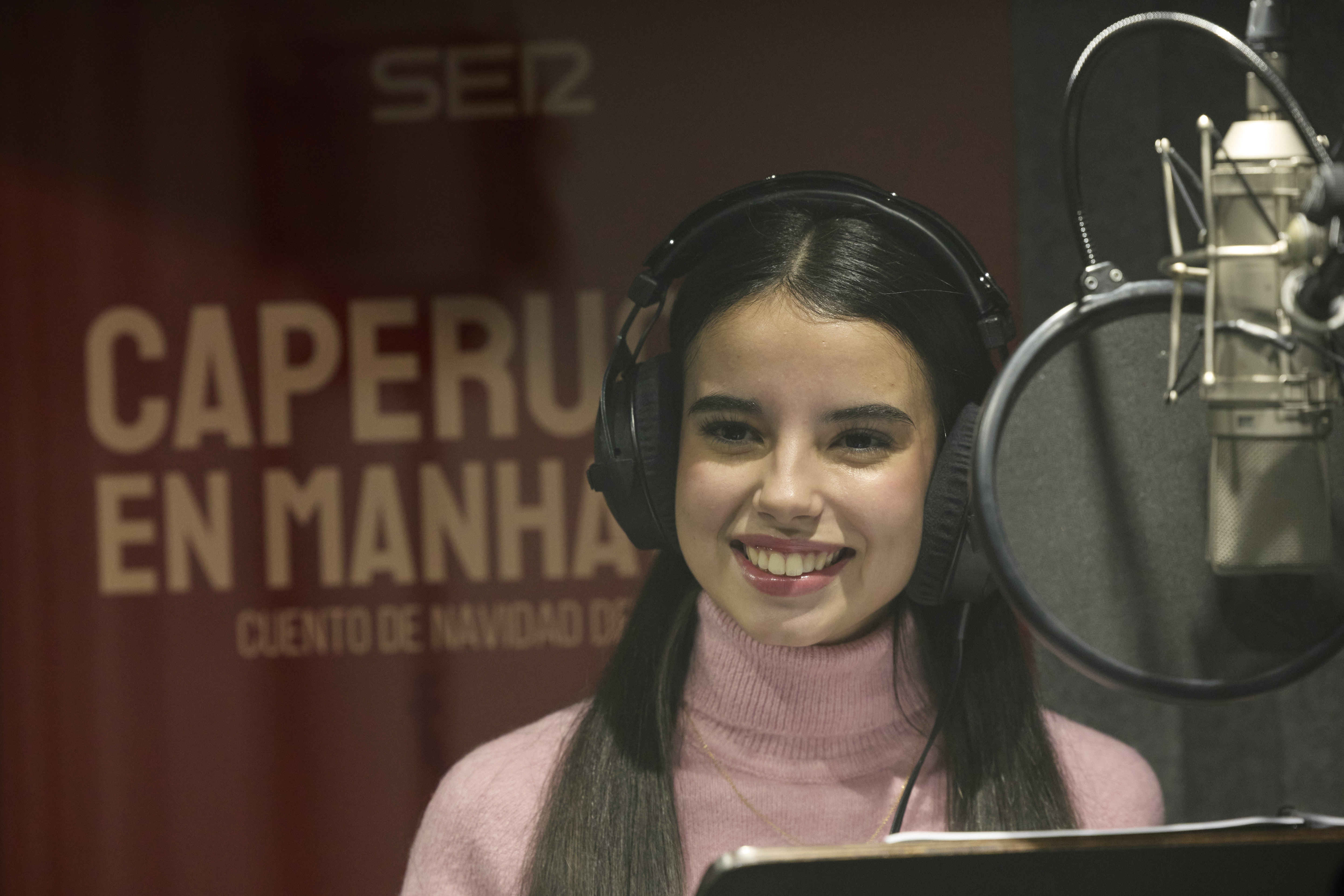 Nicole Béjar grabando el cuento de navidad con el cartel de fondo