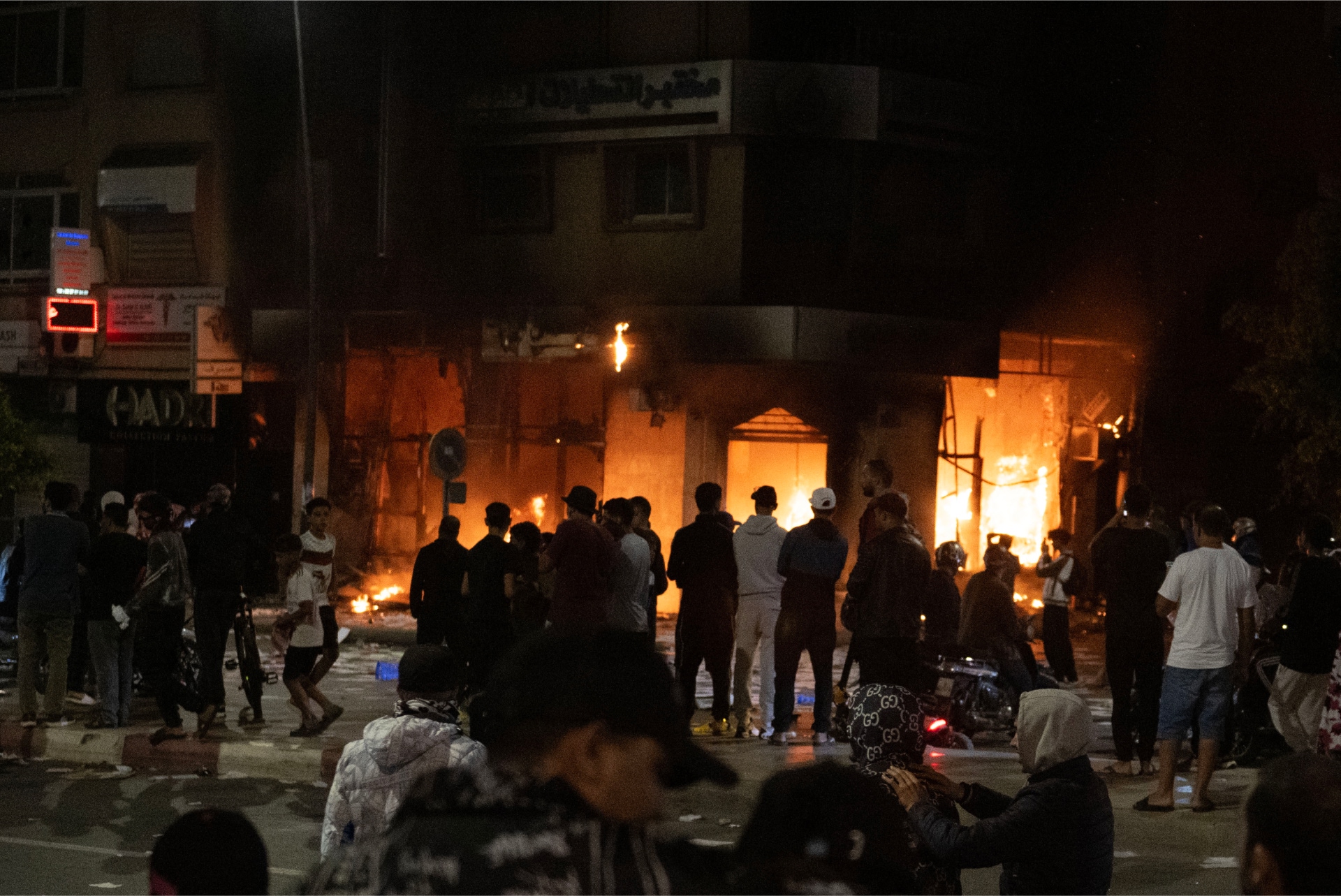 Jóvenes obserban un local en llamas en una protesta en Marruecos