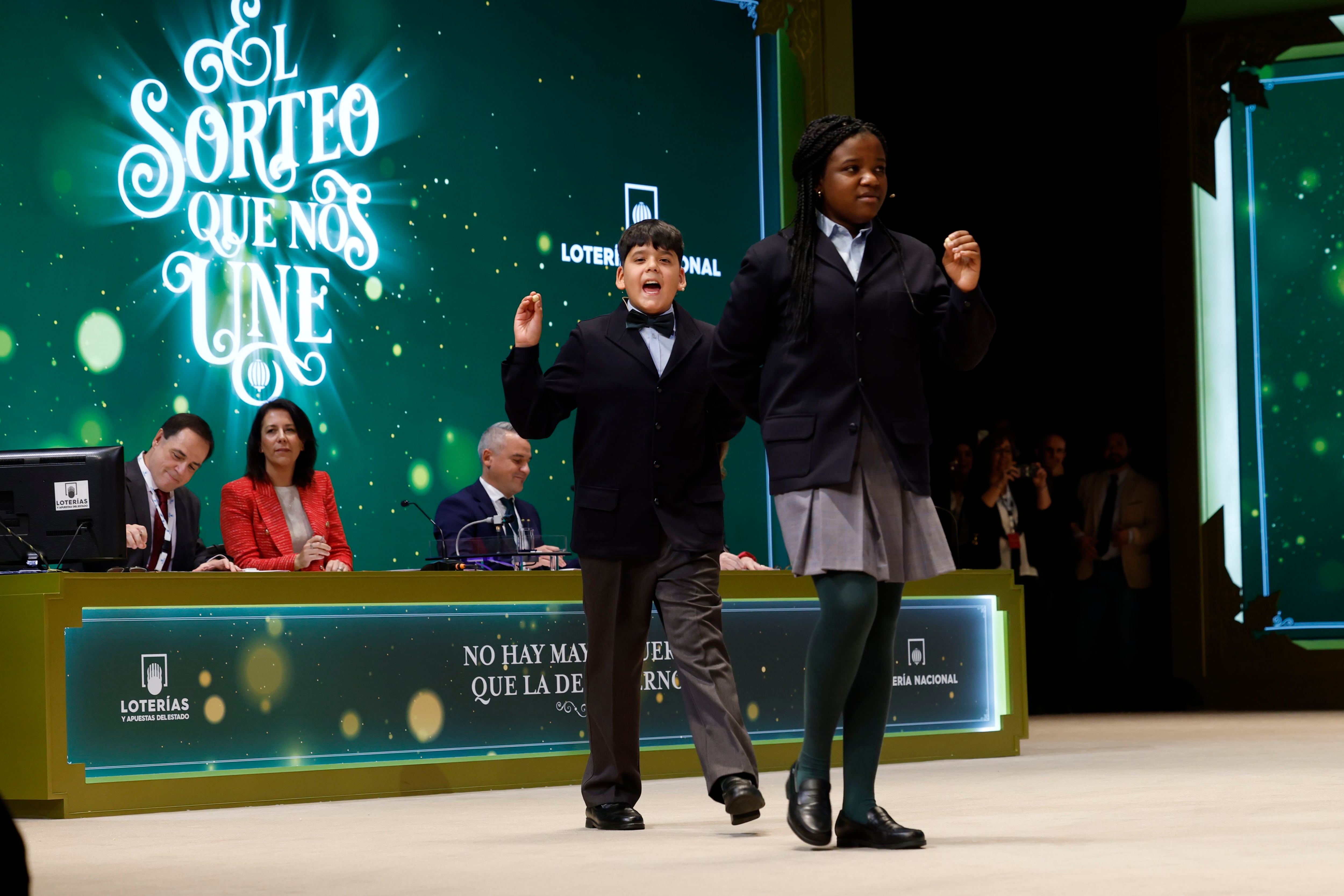 Yesica Paola Valencia Gómez y Francisco Moreno Durán se dirigen a la mesa mientras cantan el Gordo que este año ha recaído en el número 88.008 durante el sorteo extraordinario de Navidad de la Lotería Nacional este viernes en el Teatro Real de Madrid