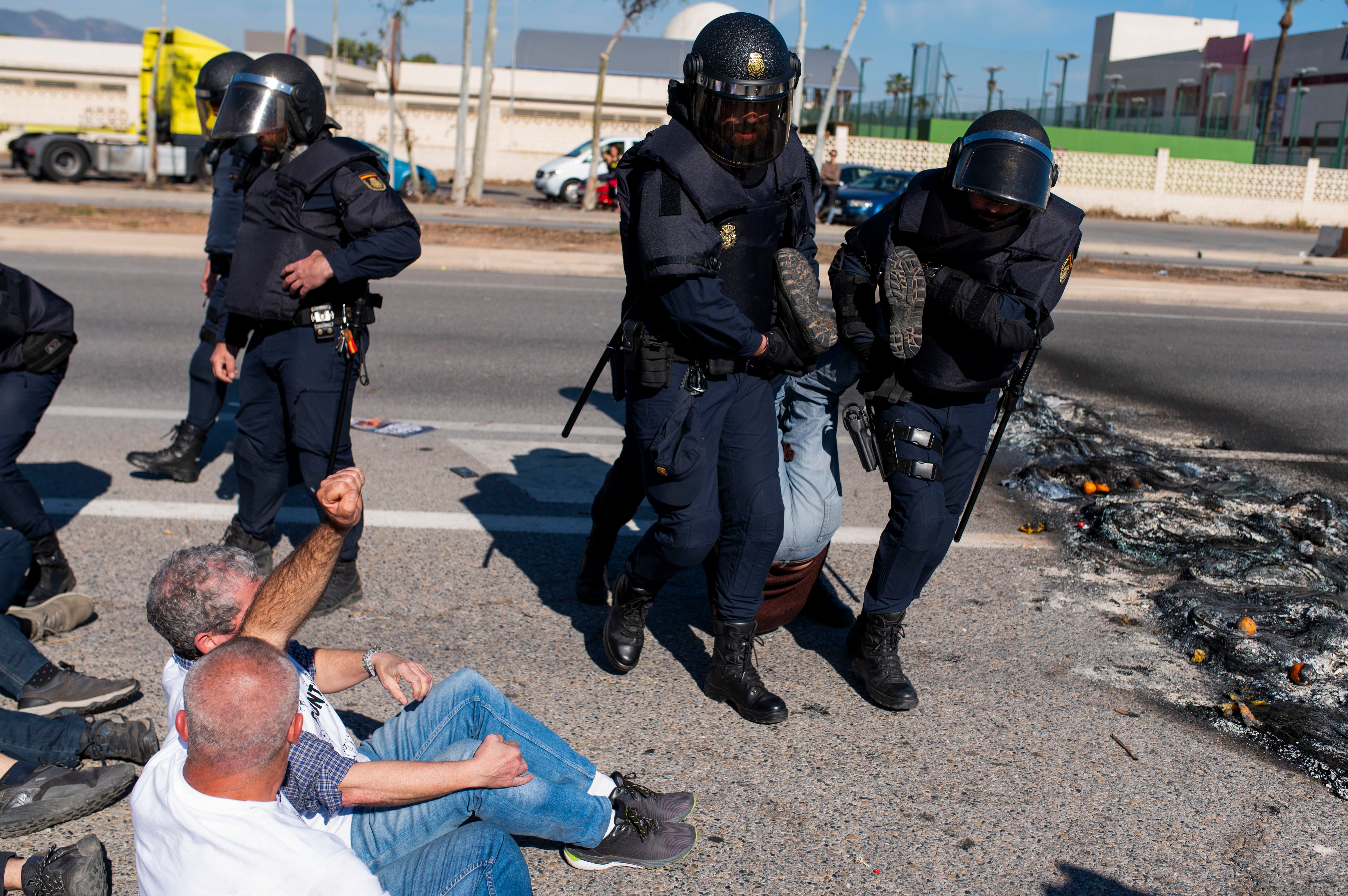 Agentes de la Policía Nacional desalojan a un manifestante de la concentración convocada por la Unió Llauradora i Ramadera.