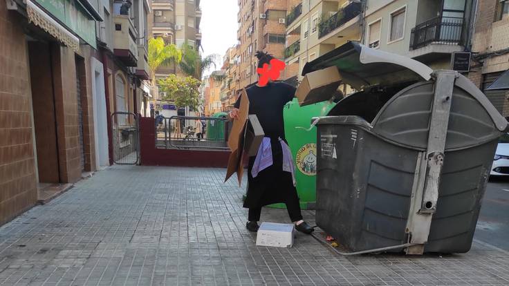 Trabajador de un restaurante de Alicante tirando cartón a un contenedor de restos