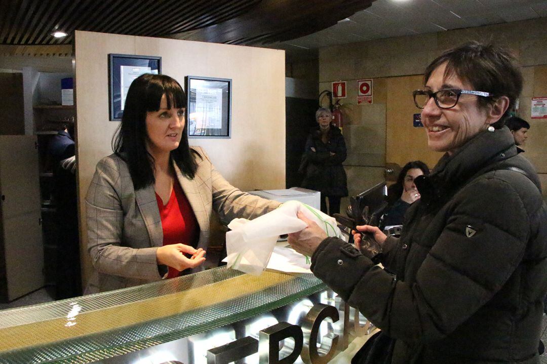 Una usuària del servei de Tràmits rep una bossa tèxtil reutilitzable per la fruita i la verdura als supermercats en el marc d'una acció organitzada per Medi Ambient dins la Setmana europea de la prevenció dels residus.