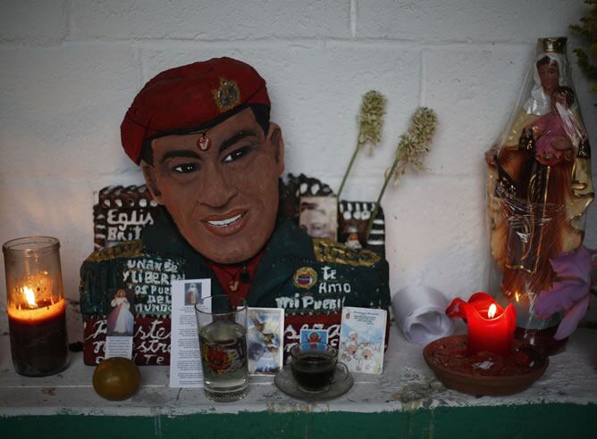 Una estatuilla de Hugo Chávez con velas e imágenes religiosas en un altar en el barrio 23 de Enero en Caracas.