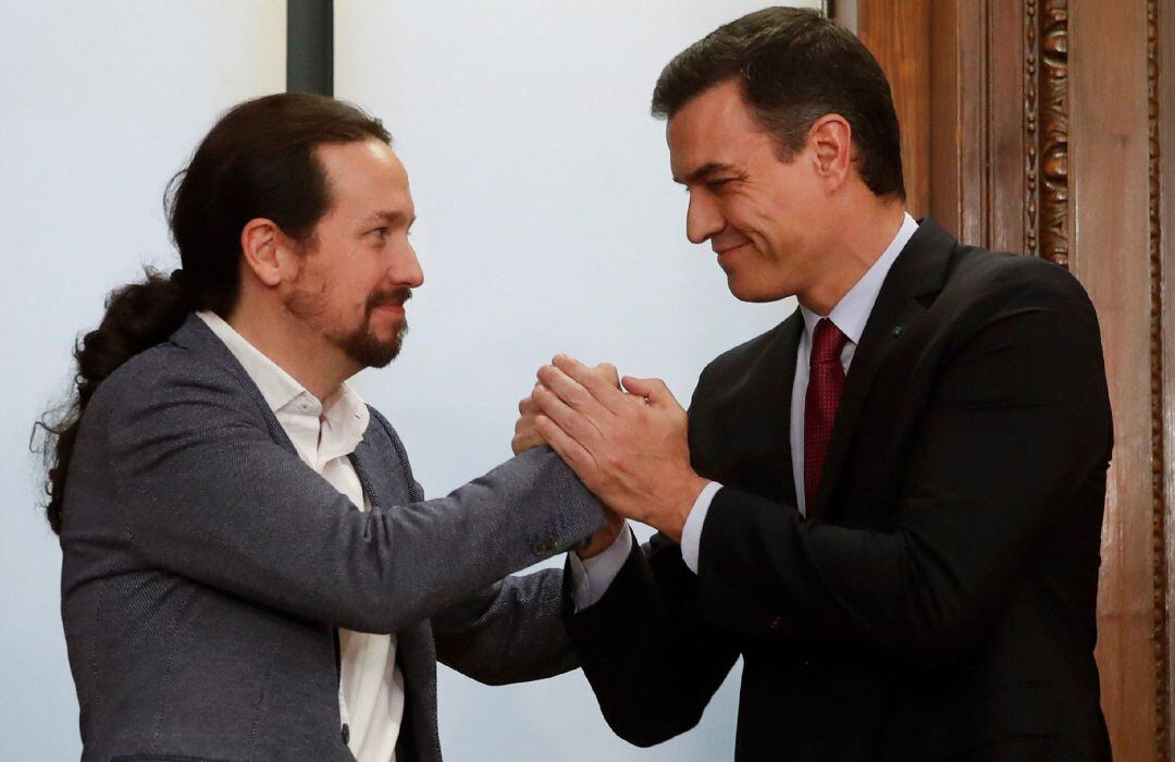 Pedro Sánchez (d) y Pablo Iglesias (i) estrechan sus manos tras el acto de firma del acuerdo programático con las principales medidas que tomará el futuro Gobierno de coalición