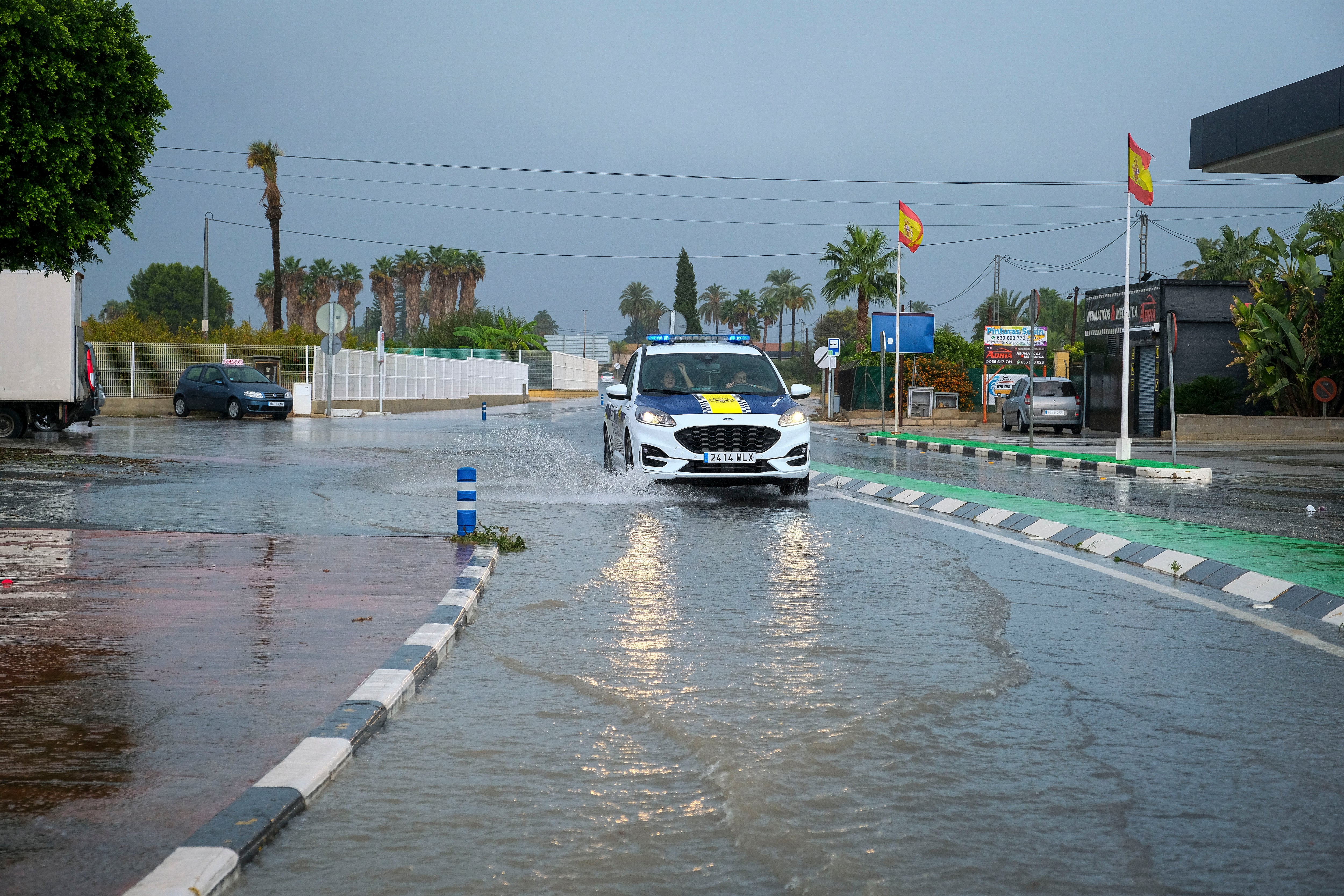 Un coche de la Policía Local circula por una calle anegada en Elche