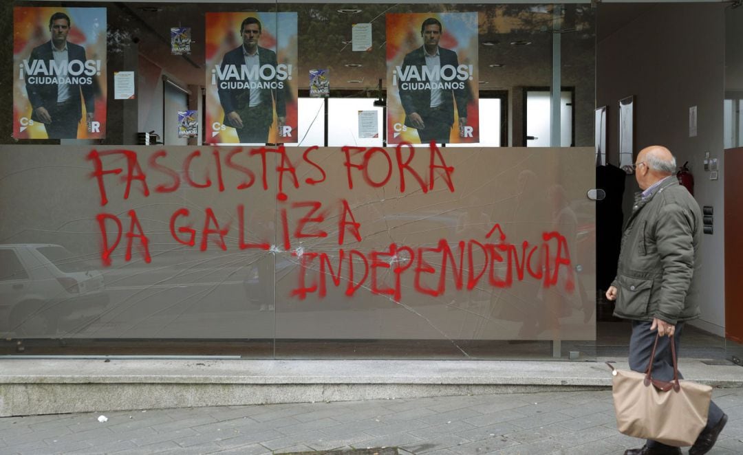 Una persona pasa delante de la sede del partido Ciudadanos, que ha aparecido rota y con la pintada &quot;Fuera fascistas de Galicia. Independencia&quot;, esta mañana en Santiago de Compostela.