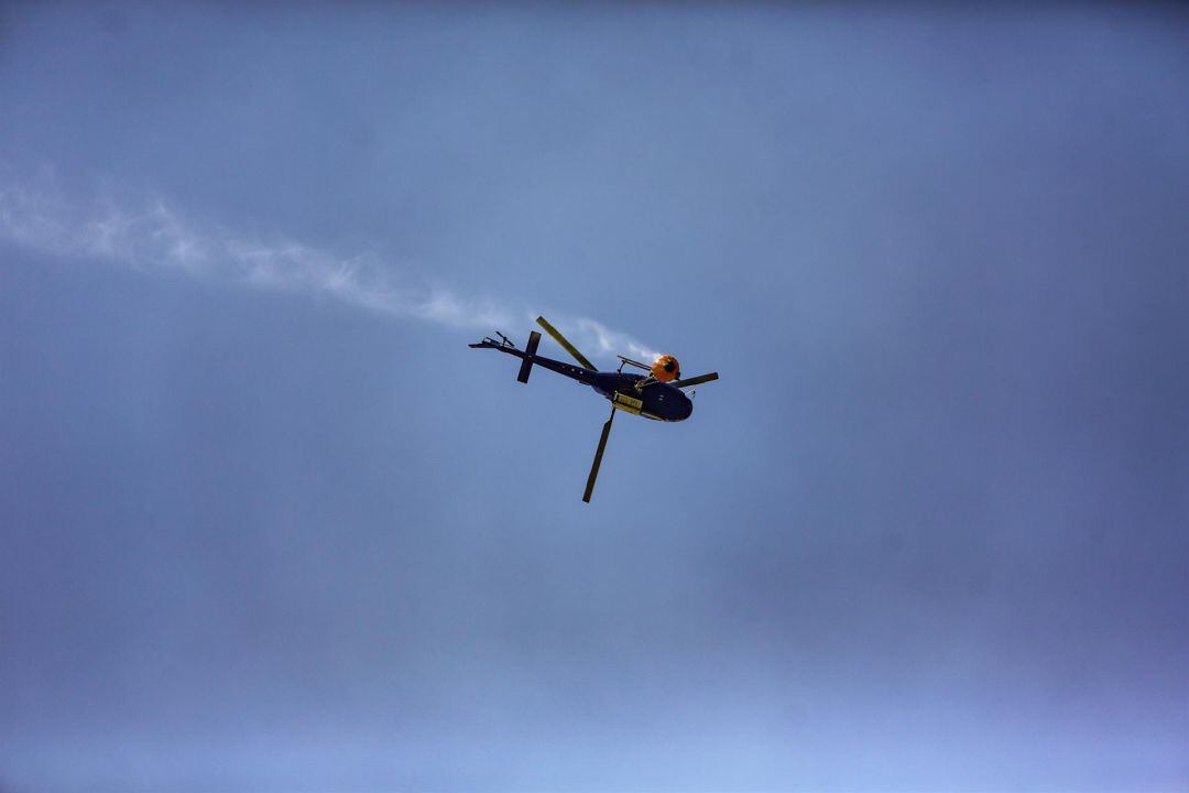 Un helicóptero transporta agua durante los trabajos de extinción del incendio del pantano de San Juan