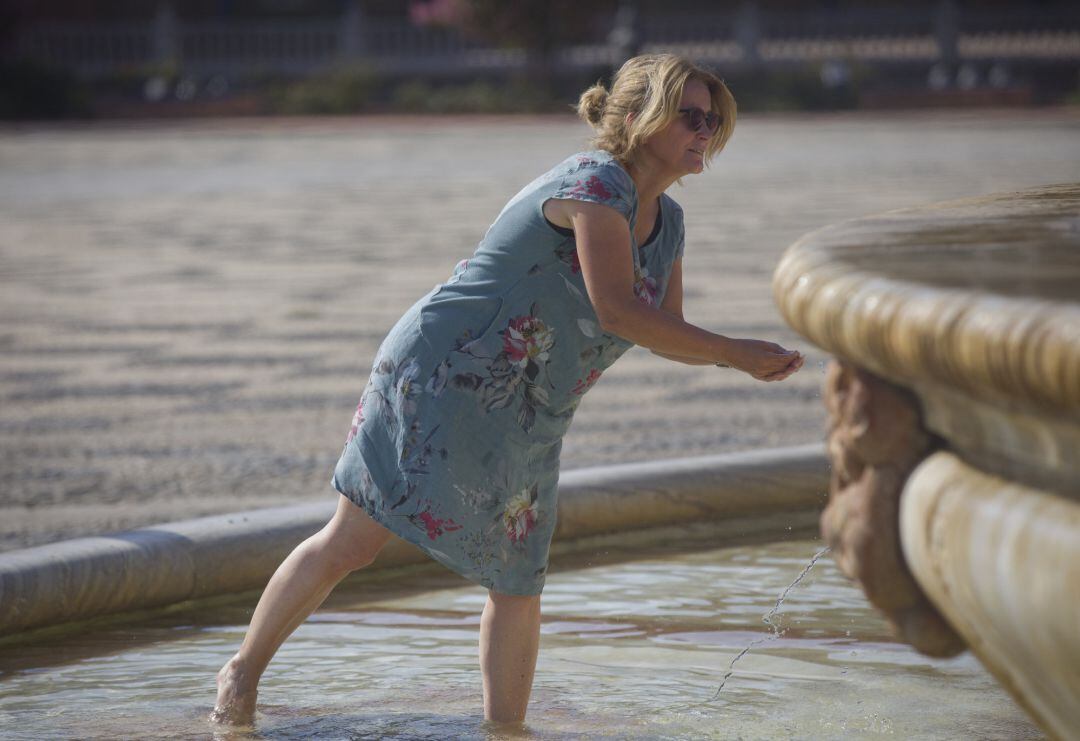 Una mujer se refresca en una fuente