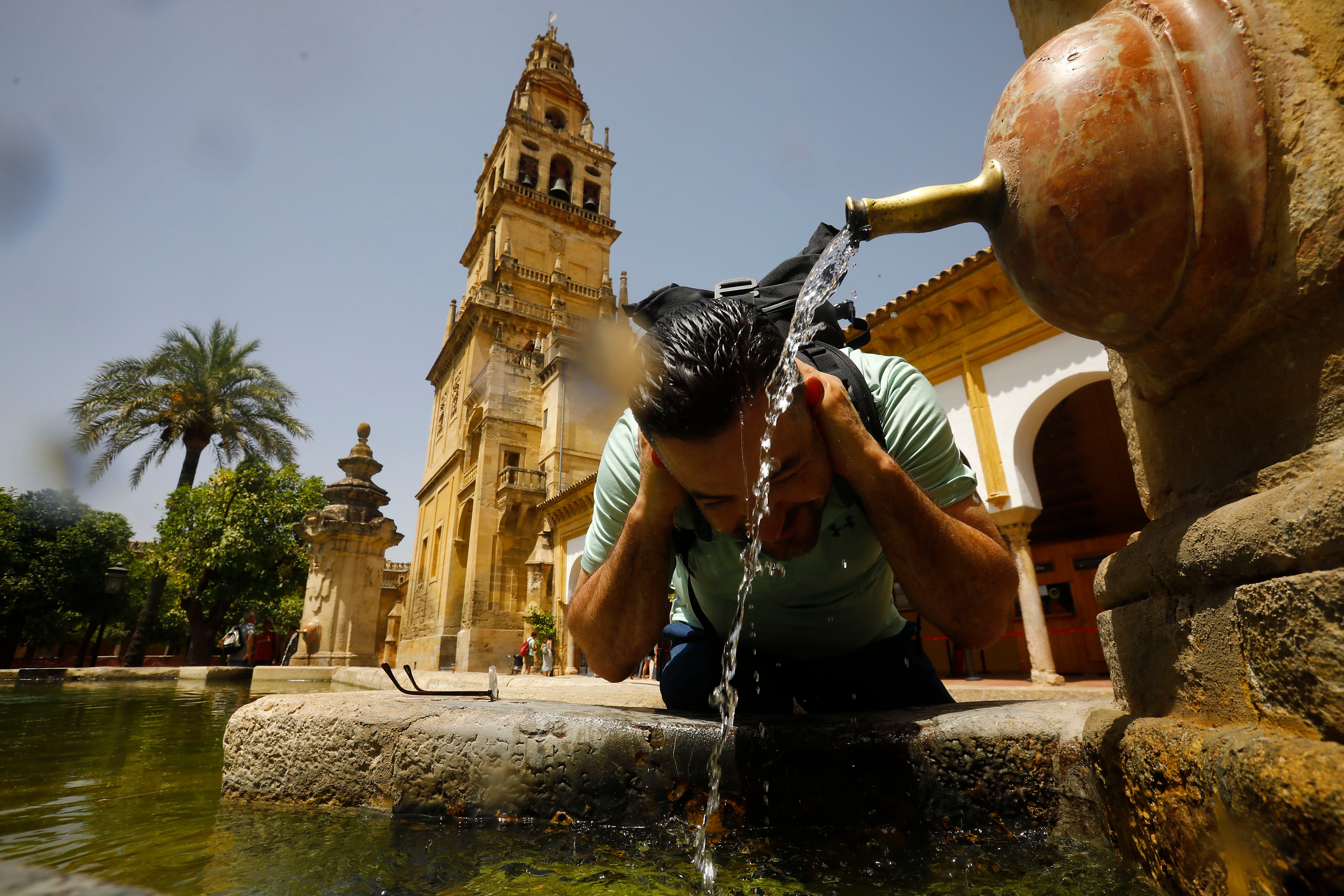 Un turista se refresca en una de las fuentes del patio de los naranjos de la Mezquita