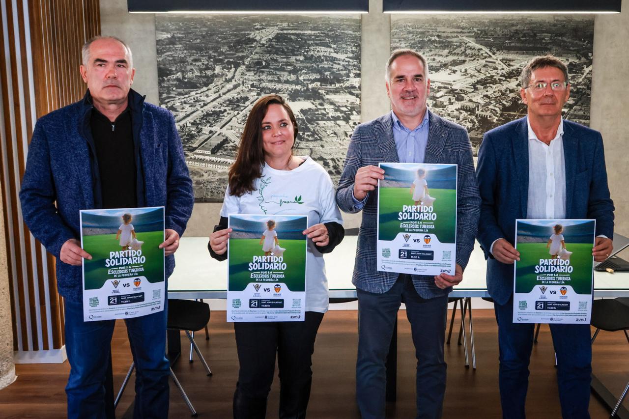 Los asistentes a la rueda de prensa posan con los carteles del partido solidario