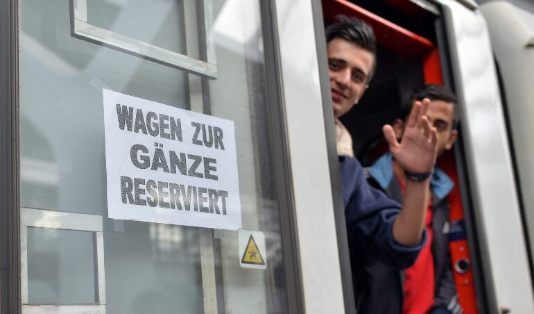 Dos refugiados saludan desde un tren con destino a Freilassing, Alemania, en la estación de Salzburgo.