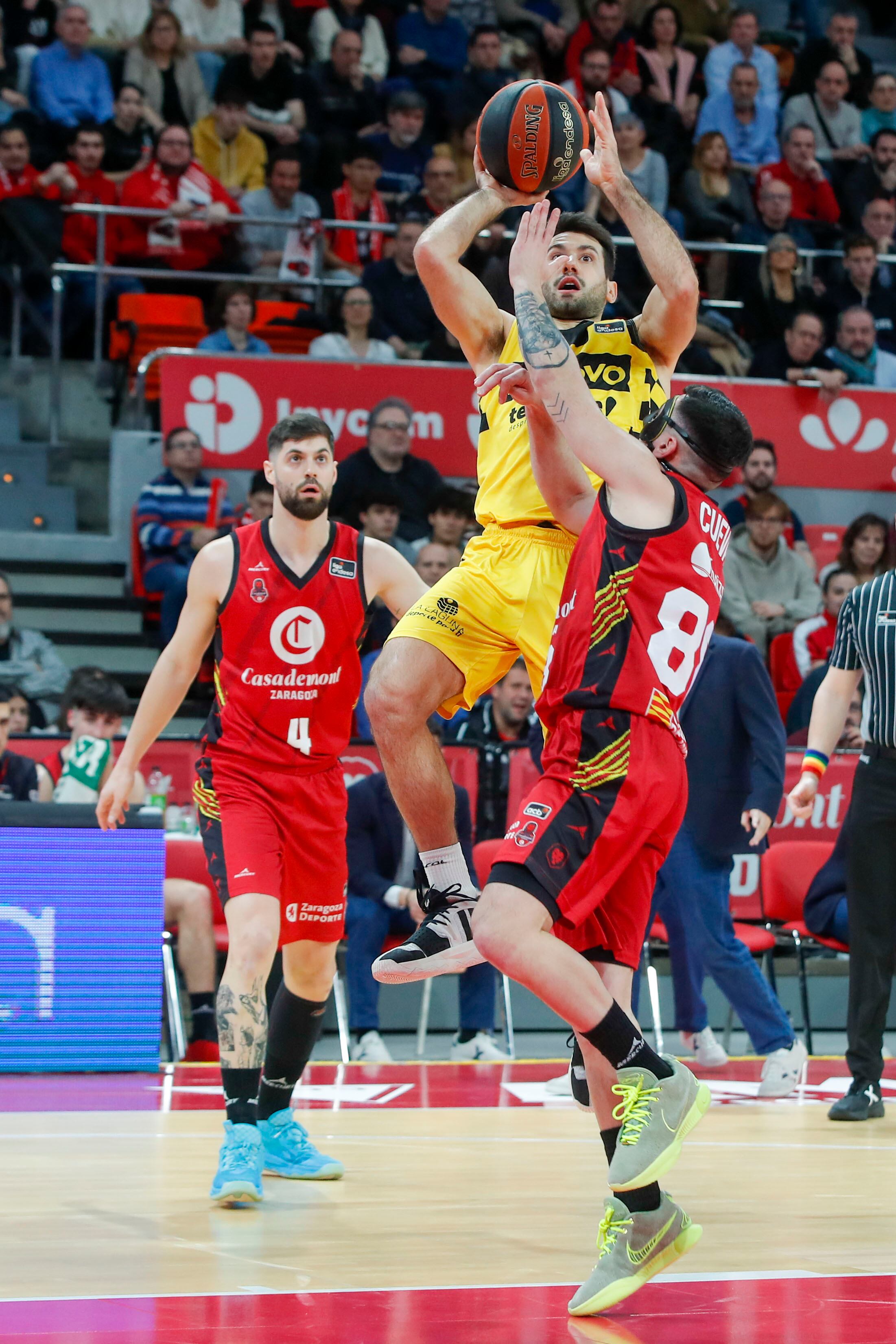 ZARAGOZA, 10/02/2024.- El escolta de Lenovo Tenerife Bruno Fitipaldo (c) lanza a canasta defendido por el cubano Yoanki Mencía (d), de Casademont Zaragoza, durante el partido de Liga Endesa que se juega hoy sábado en el pabellón Príncipe Felipe de Zaragoza. EFE/Javier Cebollada