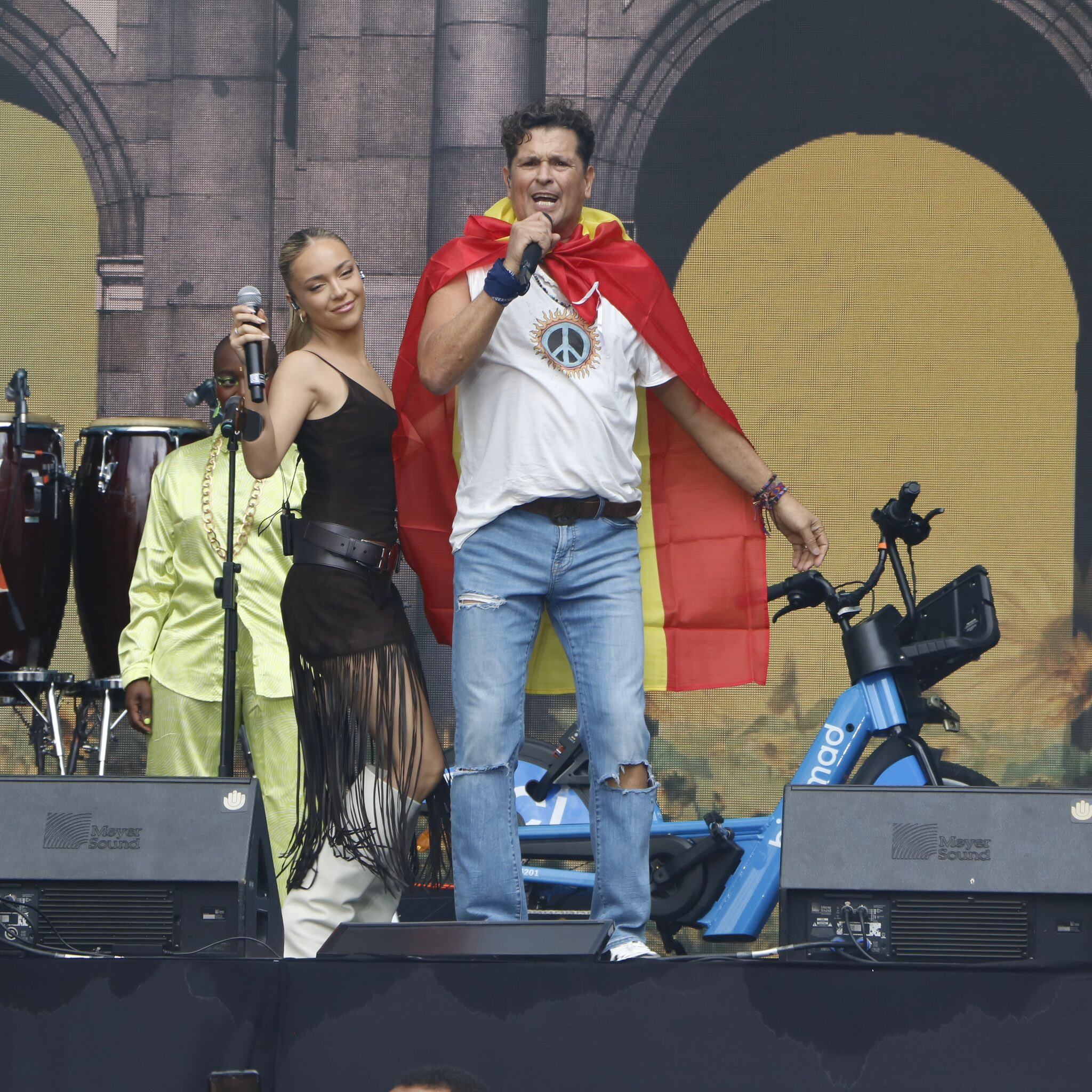 Carlos Vives y Ana Mena durante el concierto de la Hispanidad 2023 junto a una bicicleta de BiciMad, que patrocinó el evento