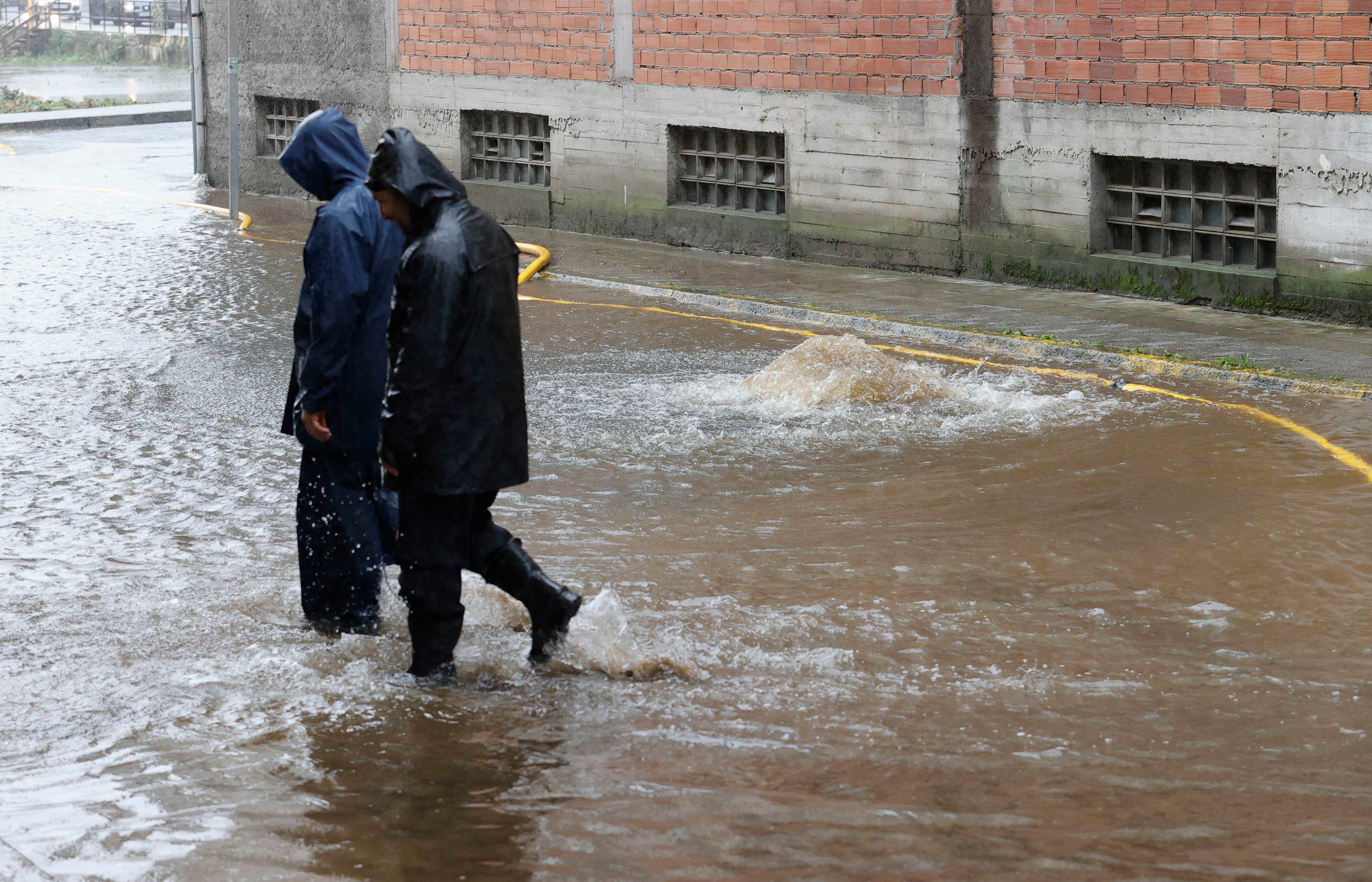 FENE (A CORUÑA), 14/11/2023.- Varias personas caminan por una calle anegada tras el desbordamiento del río Cádavo a causa de las últimas lluvias registradas en Fene (A Coruña). EFE/ Kiko Delgado
