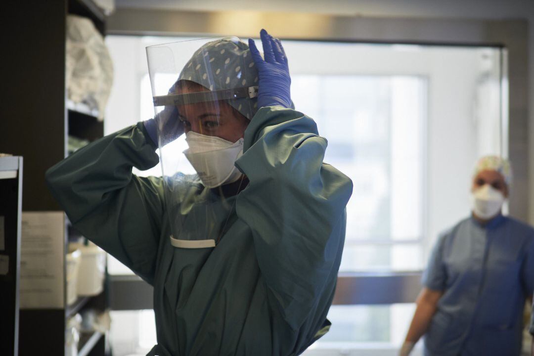Una trabajadora sanitaria se coloca una pantalla protectora antes de entrar a una habitación de la UCI de la Clínica Universidad de Navarra, en Pamplona