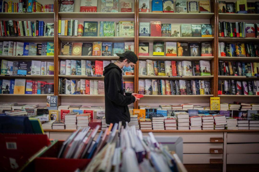 Un joven observa un libro en una librería