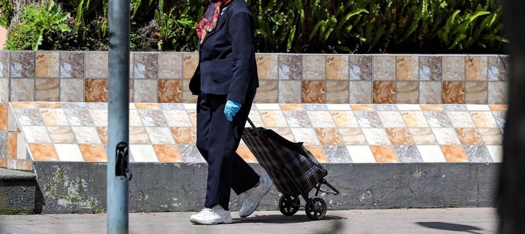 Una adulta mayor camina con su carro de compras este martes