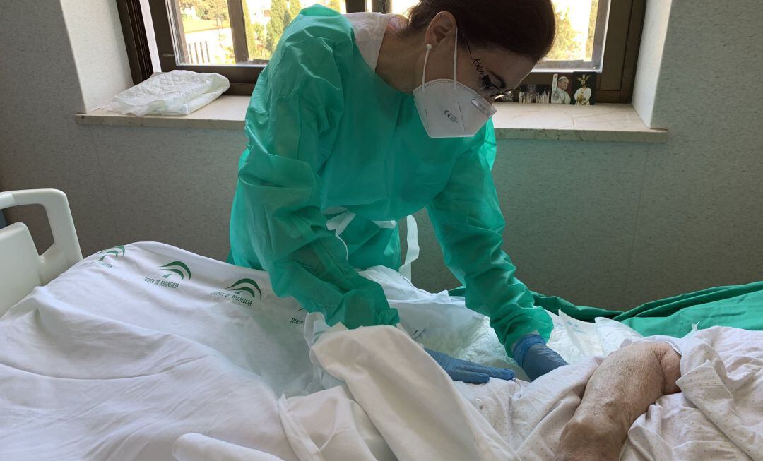 Una profesional sanitaria atiende a una persona ingresada en un hospital.