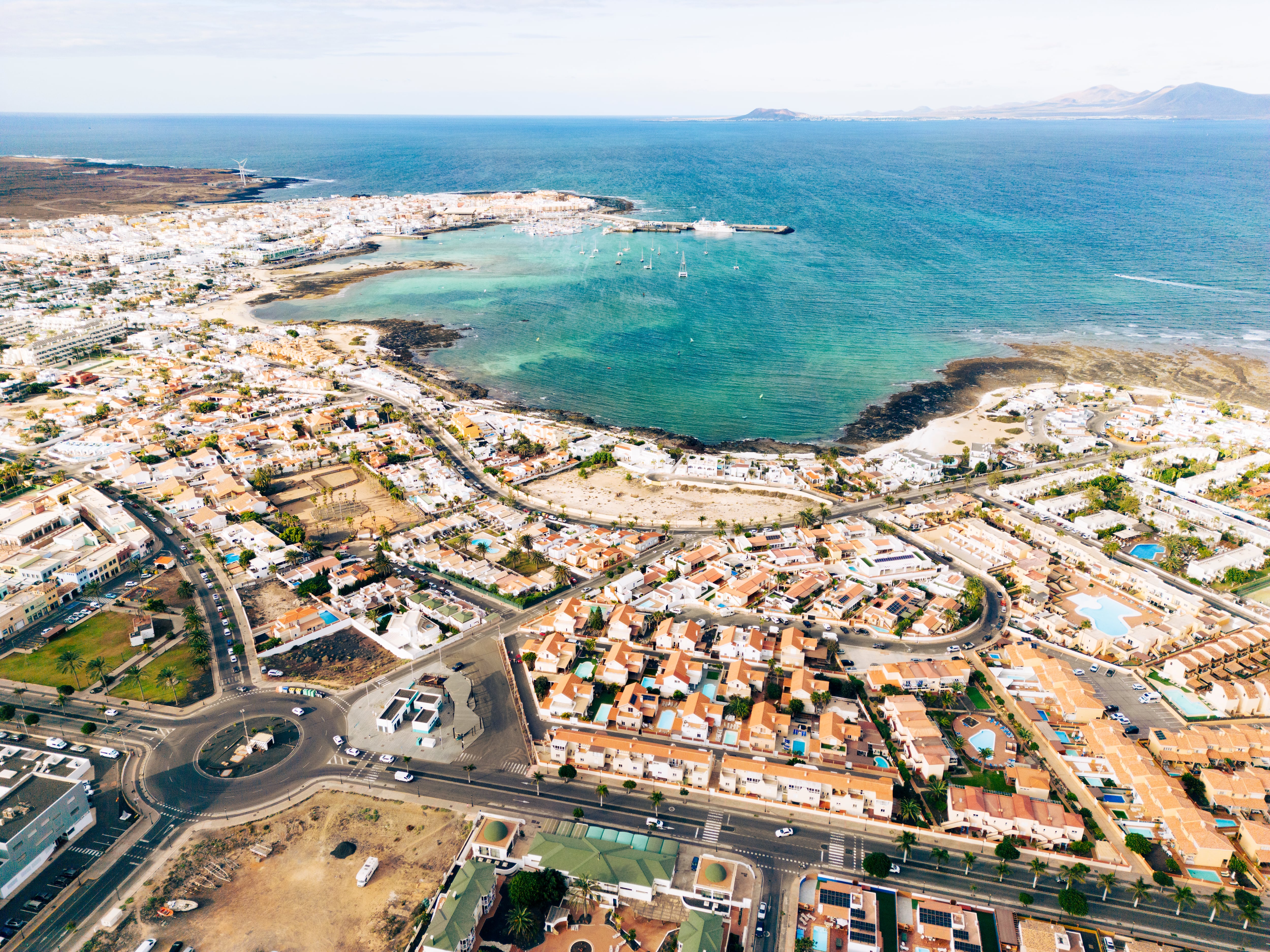 Spain, Canary Islands, Fuerteventura, Corralejo, aerial view over residential buildings and surrounding town including the sea port