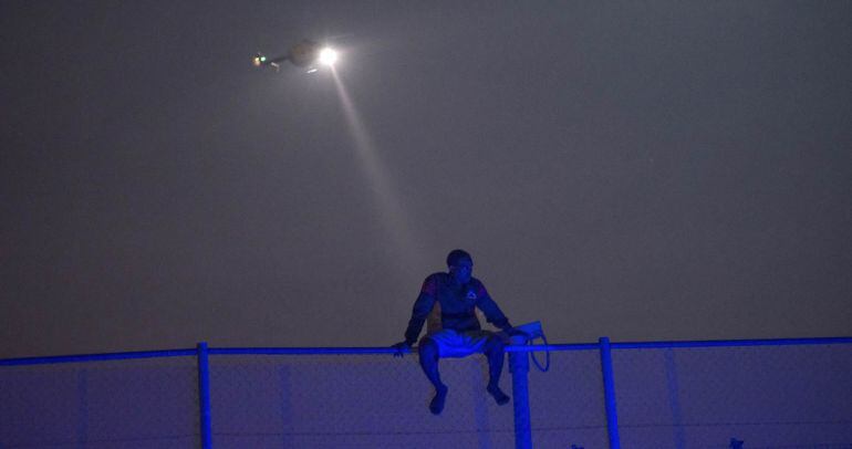 Foto de archivo de un inmigrante sobre la valla de Melilla.