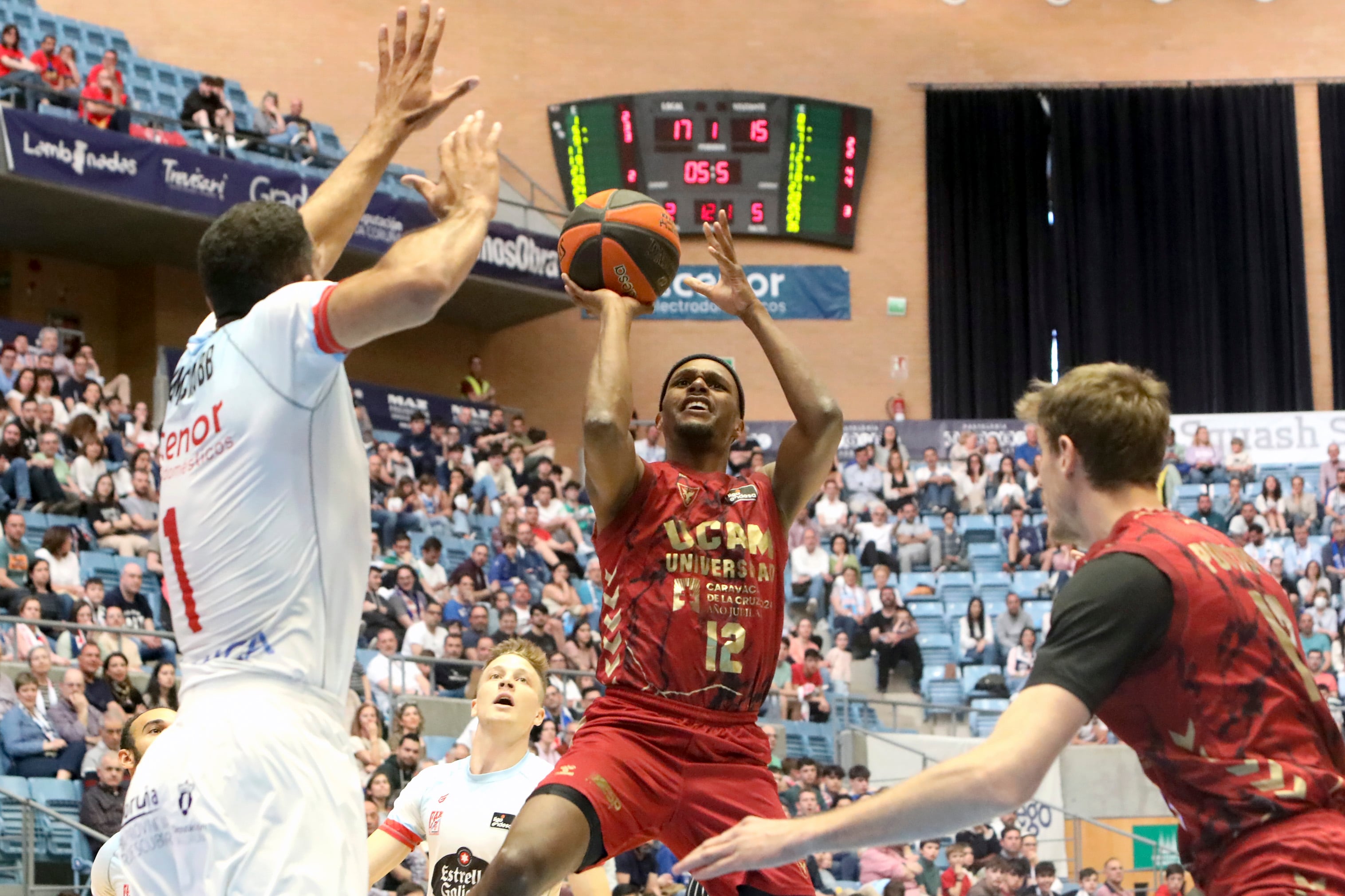 SANTIAGO DE COMPOSTELA, 08/04/2023.- El Jugador del UCAM Murcia Thad Mcfadden (c) tira a canasta ante el jugador del Obradorio, Thomas Scrubb (i), durante el encuentro de la Liga ACB que se juega hoy sábado en el Multiusos de Sar, en Santiago de Compostela. EFE/Xoán Rey.
