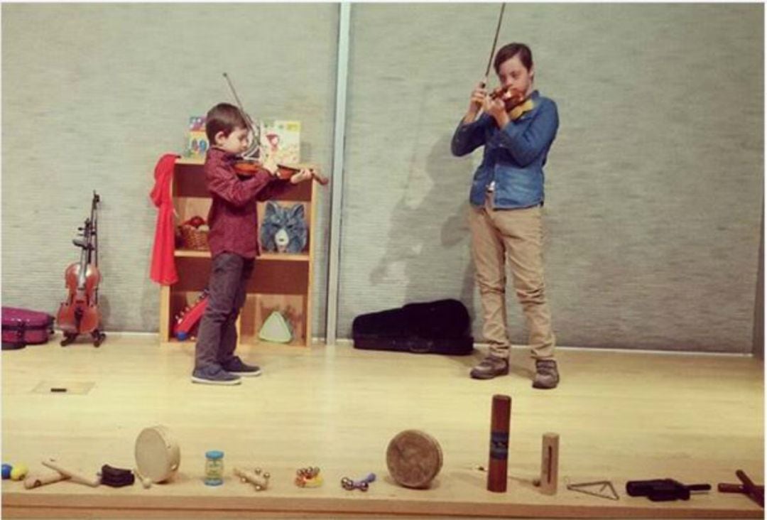 Dos niños disfrutando con sus violines