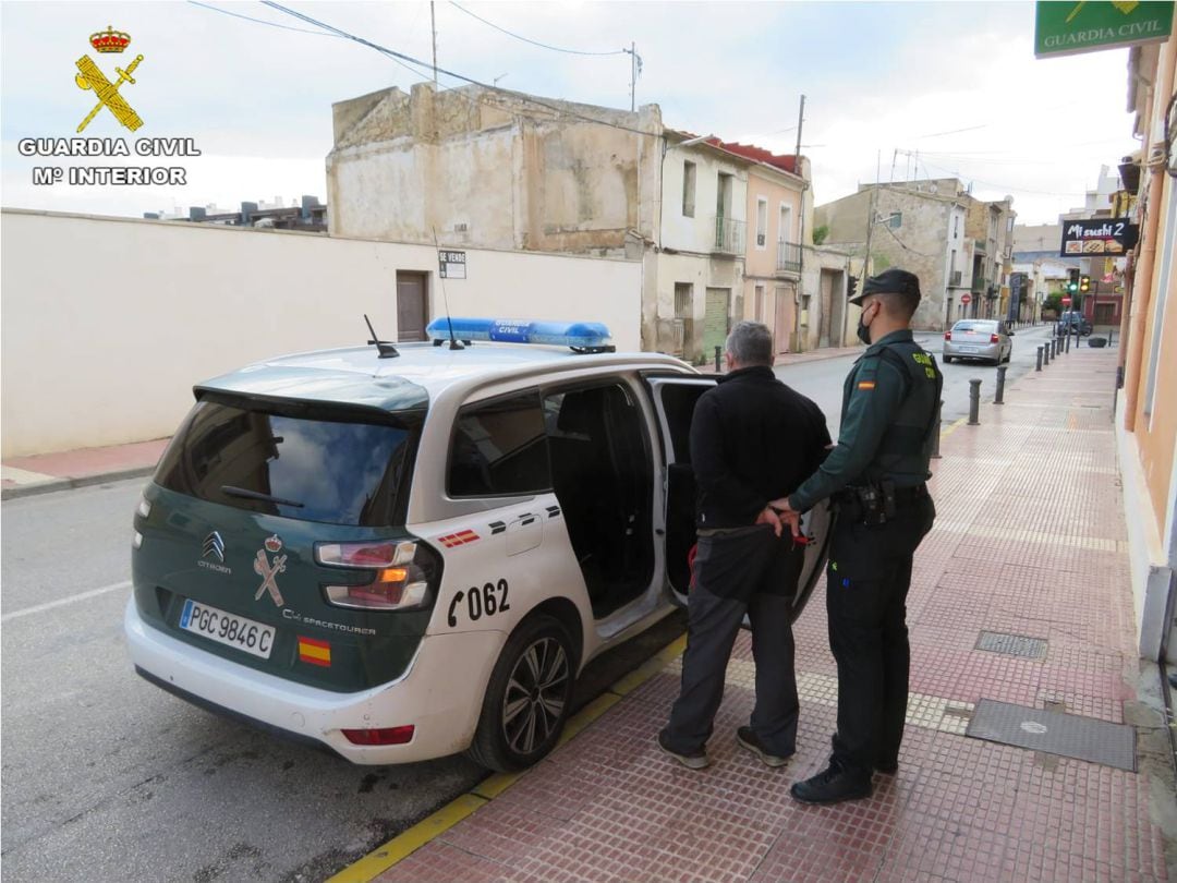 Uno de los detenidos es introducido en el vehículo de la Guardia Civil para su traslado