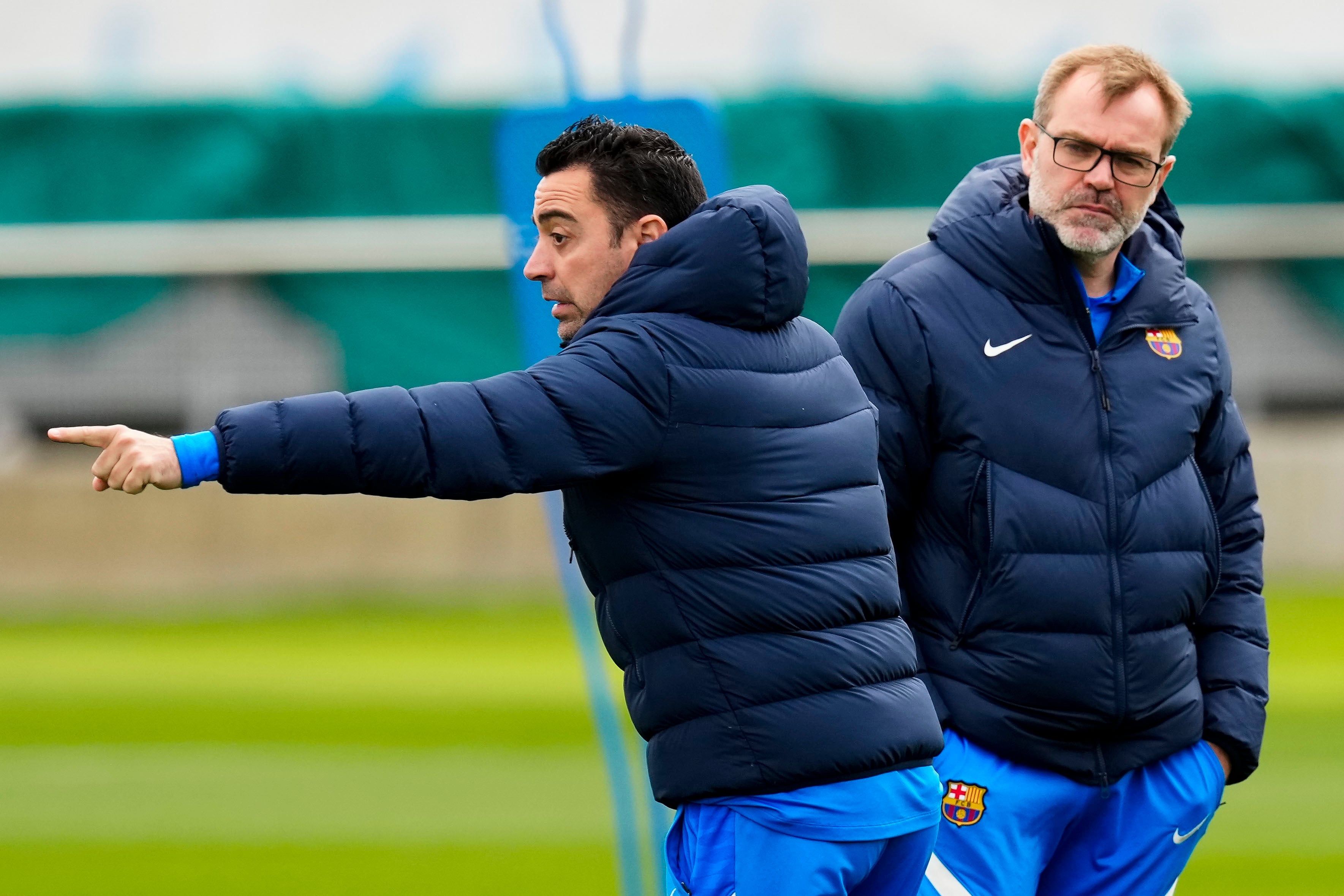 El entrenador del FC Barcelona, Xavi Hernández (c), conversa con su asistente Oscar Hernández durante un entrenamiento