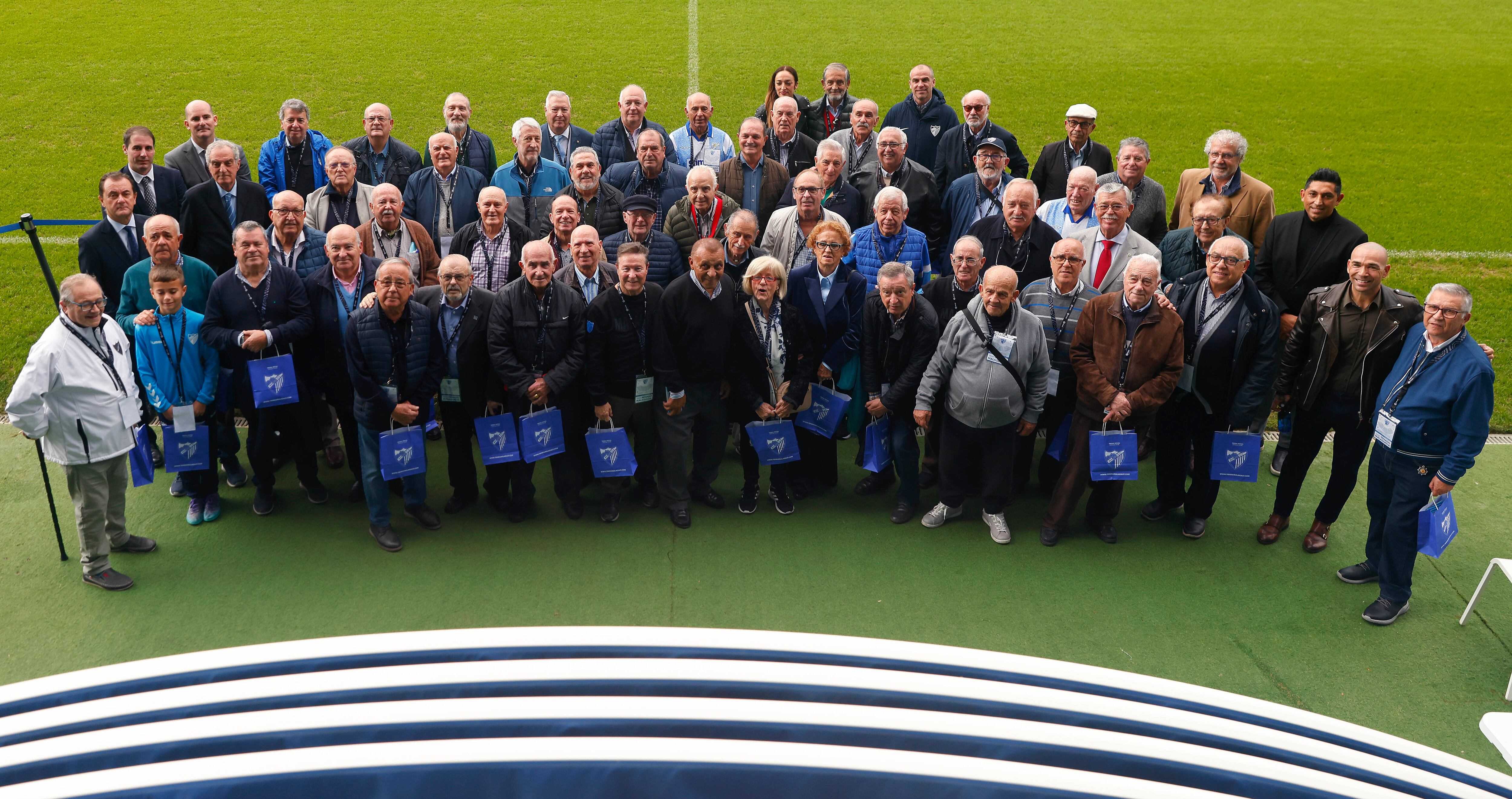 Abonados antiguos del Málaga posan en el césped de La Rosaleda