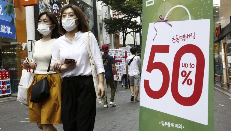 Dos mujeres llevan mascarilla mientras pasean por la calle comercial Myeong-dong en Seúl (Corea del Sur).