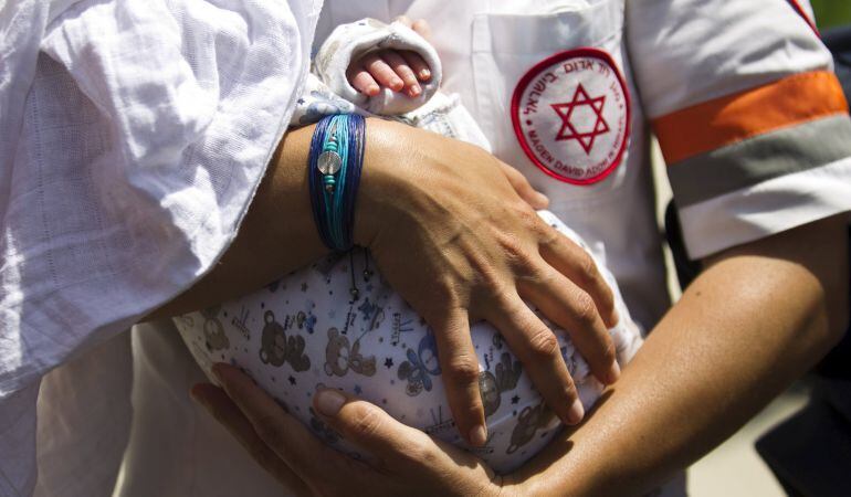 Un médico israelí con un bebé nacido gracias a la maternidad subrrogada siendo evacuado de Nepal.