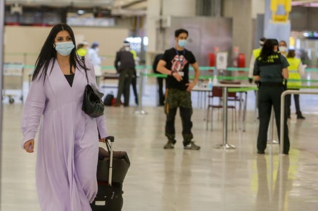 Agentes de la Guardia Civil y personal del Aeropuerto de Madrid-Barajas Adolfo Suárez controlan la llegada de pasajeros el día en el que se estrena el triple control sanitario de seguridad.