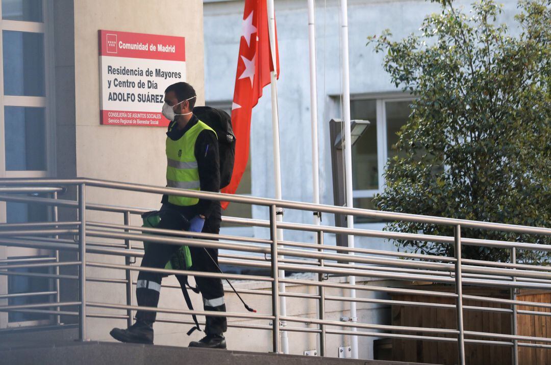 Un militar de la UME protegido con mascarilla y con el material desinfectante necesario se dirige a la puerta de una residencia de ancianos de Madrid