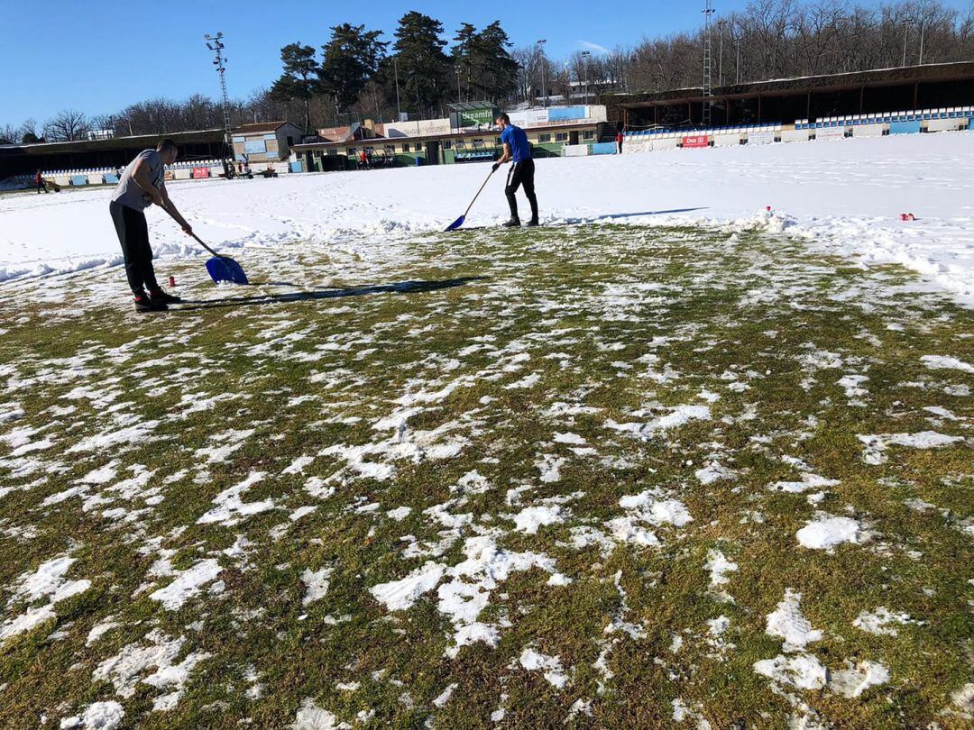 Jugadores del CD La Granja limpiando de nieve el campo