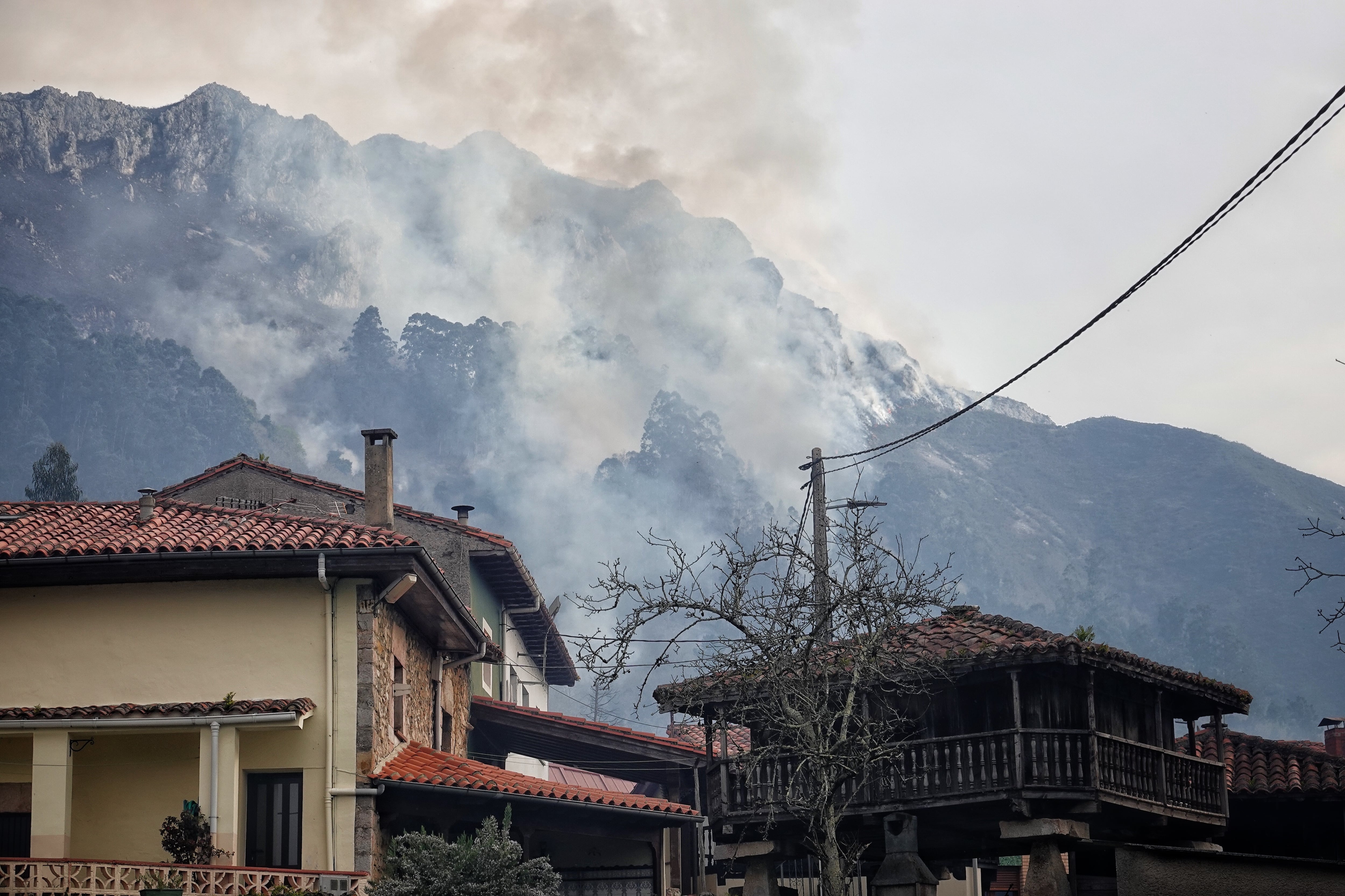 Humo del incendio tras las casas de Parres (Asturias).