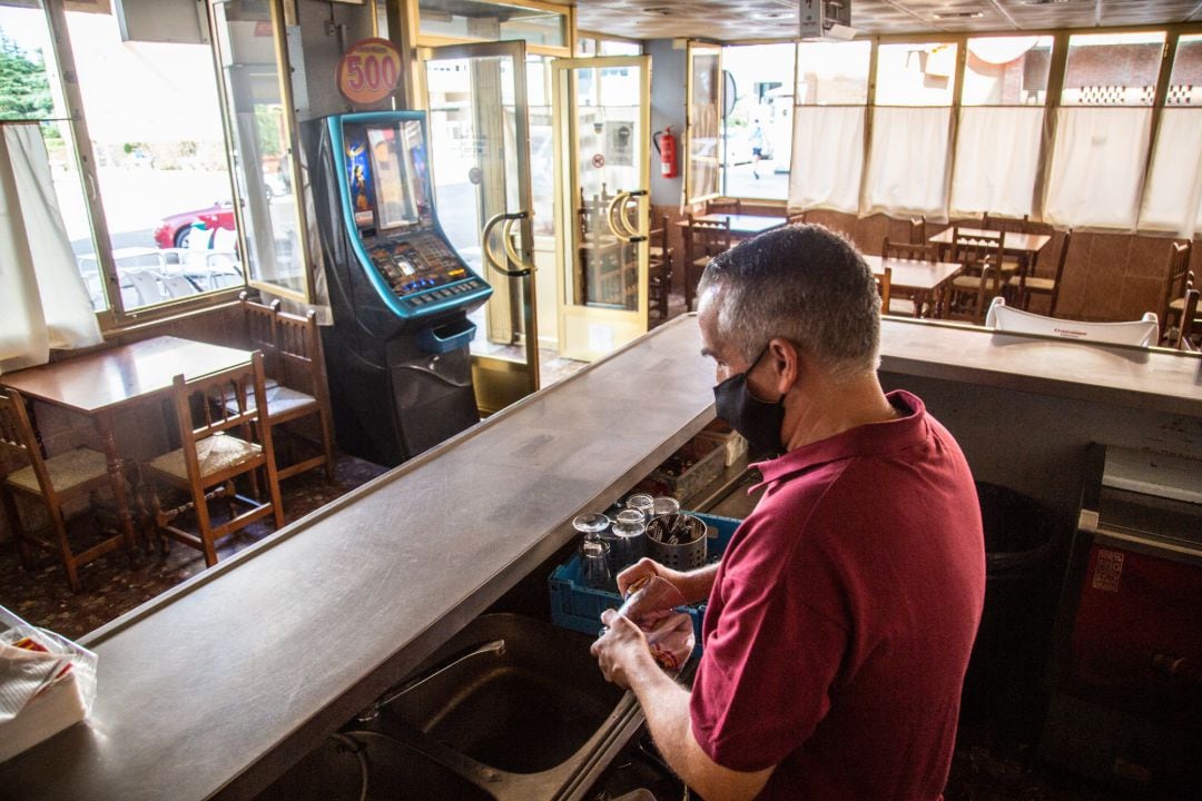 Un camarero seca varios vasos en un bar