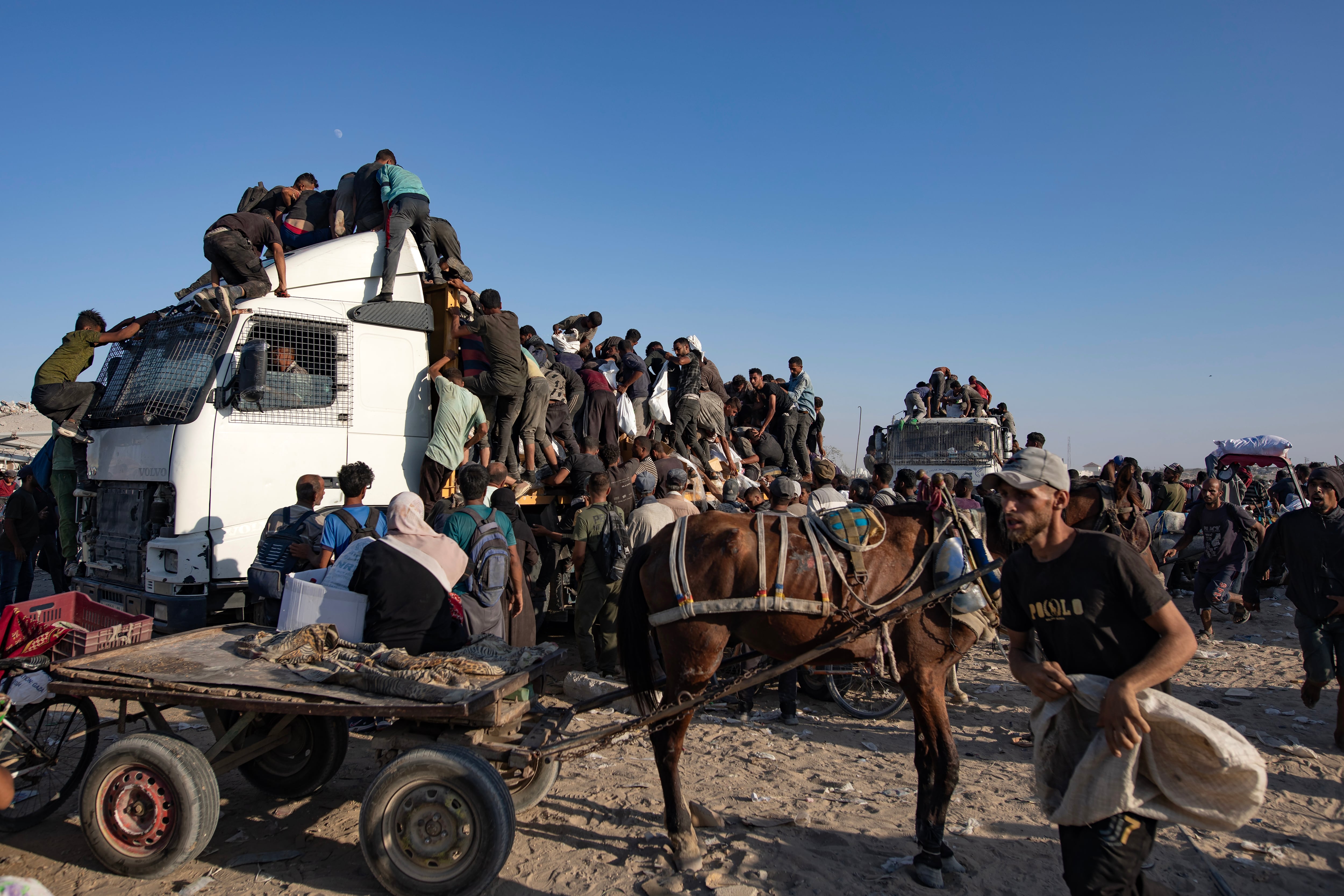 Palestinos desplazados internos suben a camiones de ayuda humanitaria para conseguir comida cerca de un punto de distribución de alimentos en el corredor de Morag este lunes, al sur de Jan Yunis (Gaza).