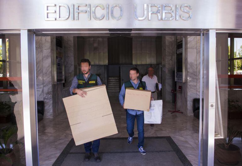 Dos agentes sacan unas cajas del edificio de oficinas en la calle Blas Infante de Sevilla donde se ha desarrollado hoy uno de los registros en el marco de la Operación Reata en la que han participado la Unidad Central Operativa (UCO) de la Guardia Civil y