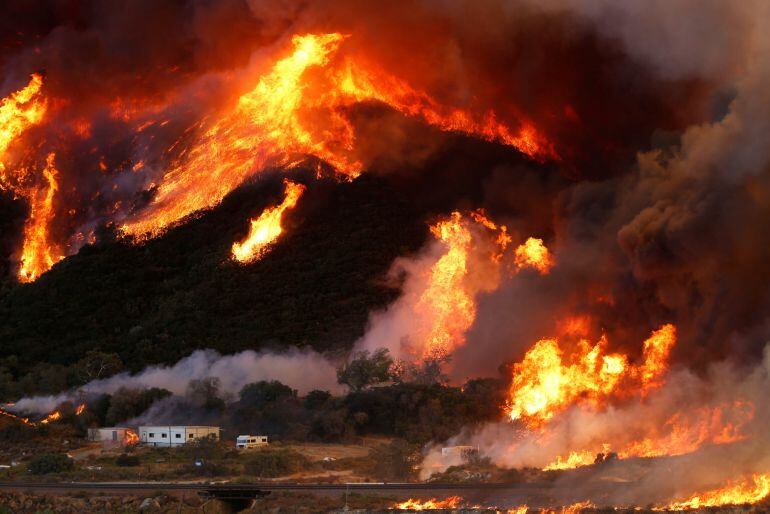 Flames whipped by strong winds burn though a hillside before destroying camper vans during the Blue Cut Fire in San Bernardino County, California, U.S. August 17, 2016. REUTERS Patrick T Fallon TPX IMAGES OF THE DAY