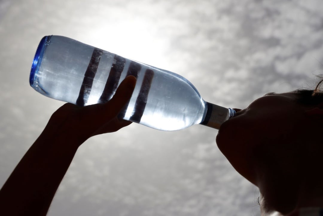 Una mujer bebe agua en la calle 