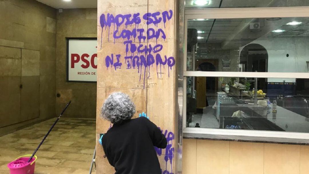 Personal de limpieza trabaja en eliminar una de las pintadas en la sede del PSRM-PSOE