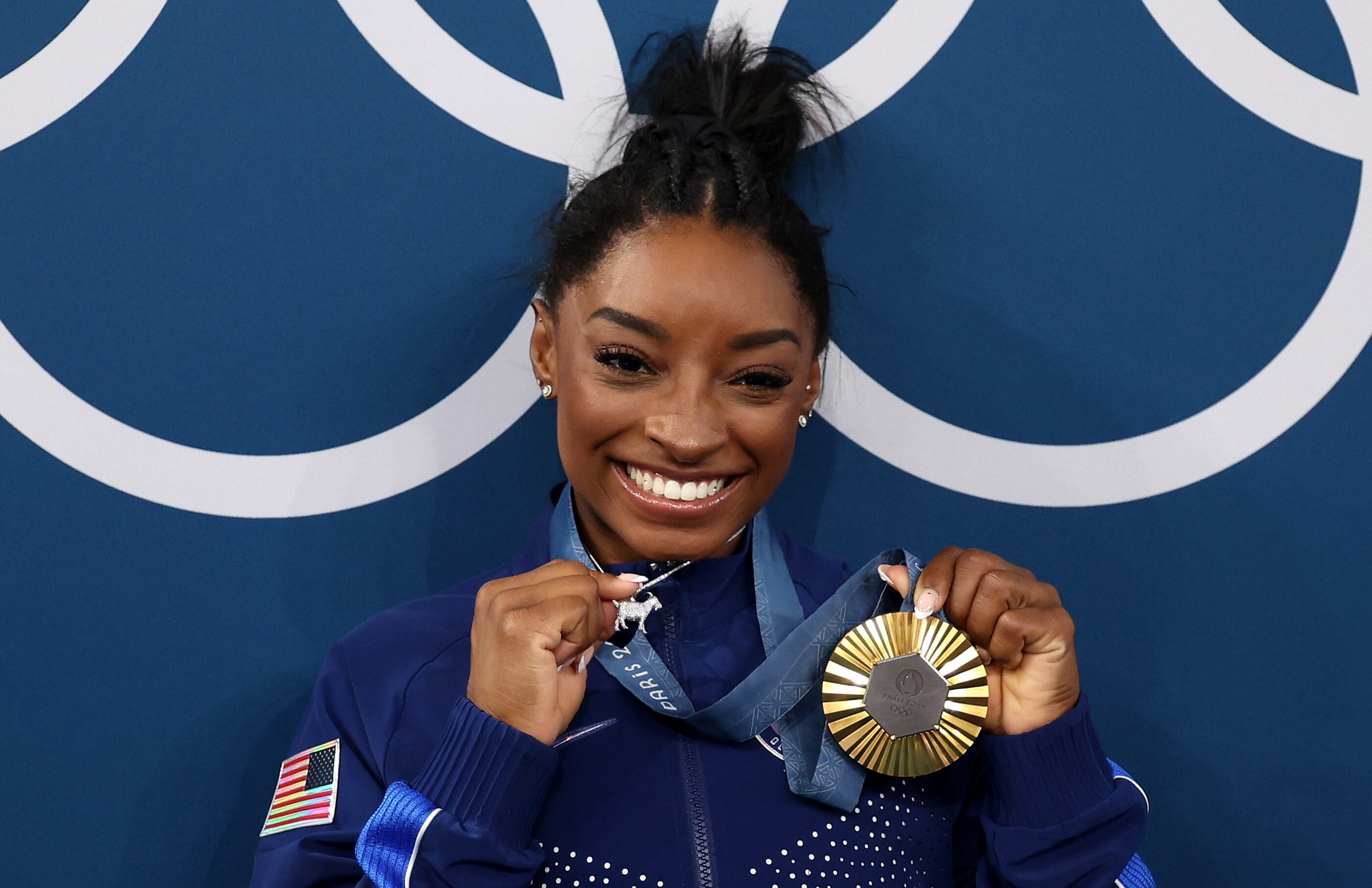 Simon Biles mostrando su medalla de oro y su colgante en forma de cabra