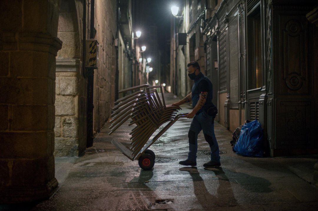 Un hombre recoge las sillas de una terraza en la Plaza Mayor de Ourense.