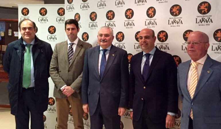El presidente del Consejo general de Hermandades y Cofradías de Sevilla, Carlos Bourrellier, en el centro de la imagen junto a los responsables del Grupo La Raza y los miembros de su junta superior