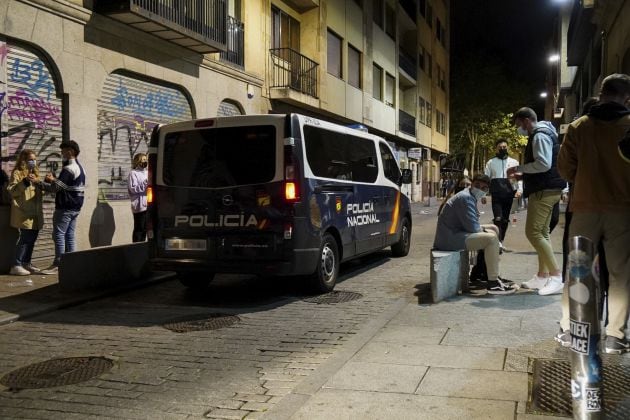 Un furgón de la policía nacional pasa junto a varias personas en ambiente festivo, en una céntrica calle de Salamanca, una semana después del fin del estado de alarma, a 15 de mayo de 2021