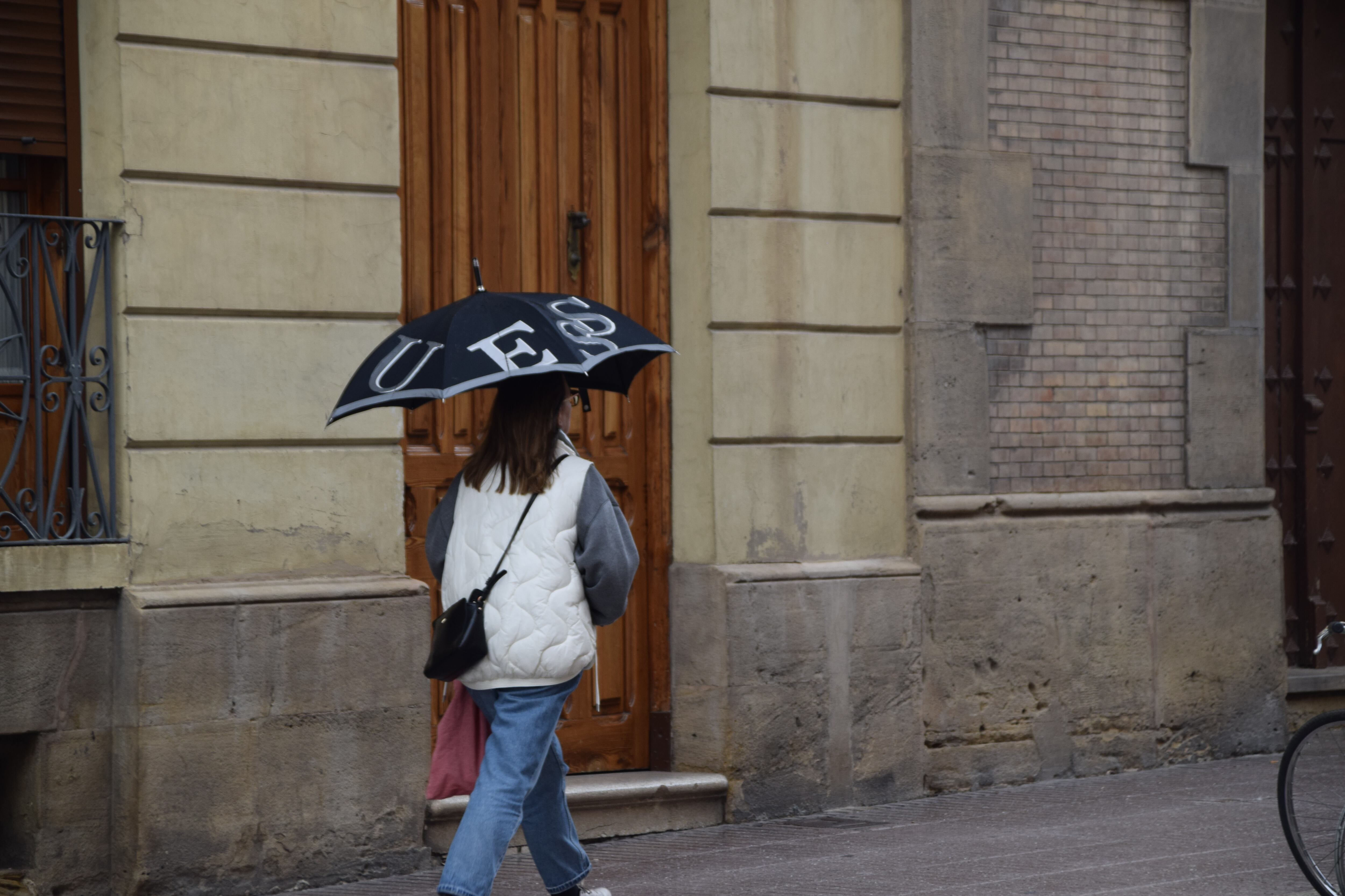 Oscenses paseando con paraguas bajo la lluvia