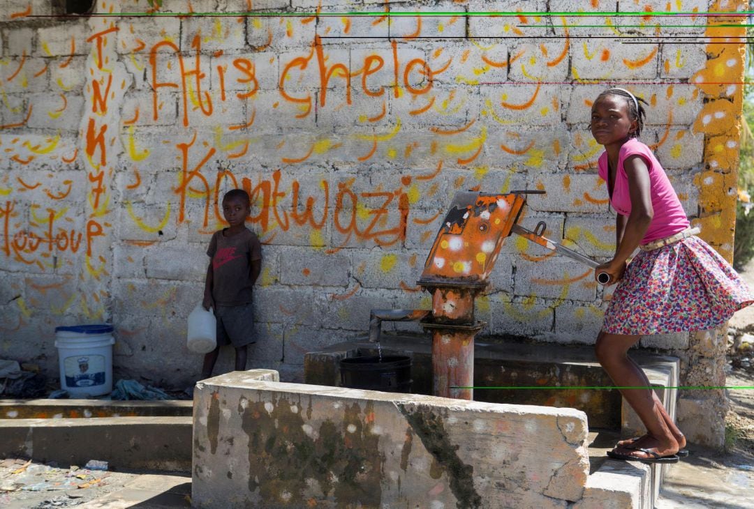 Una niña bombea agua de un pozo, este sábado, en el barrio La Plaine, en Puerto Príncipe (Haití)