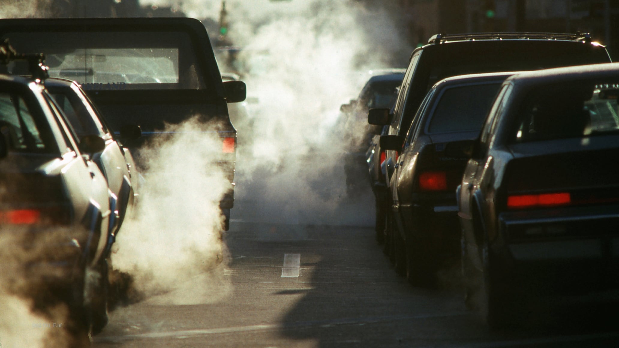 Humo procedente del tubo de escape de vehículos en la ciudad