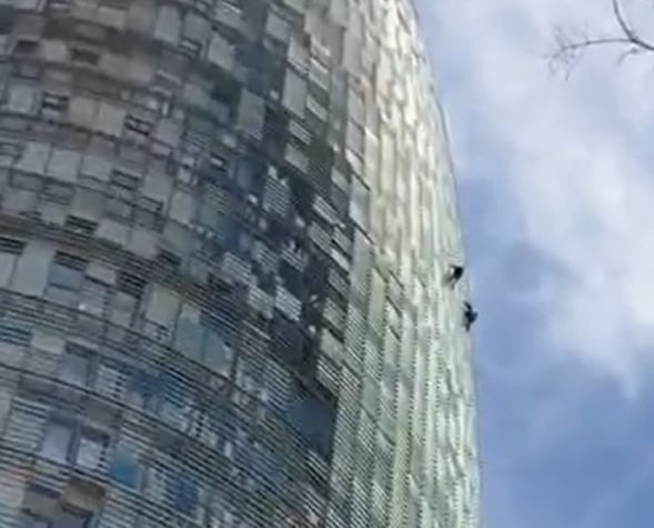 Dos hombres escalan la Torre Glòries de Barcelona.