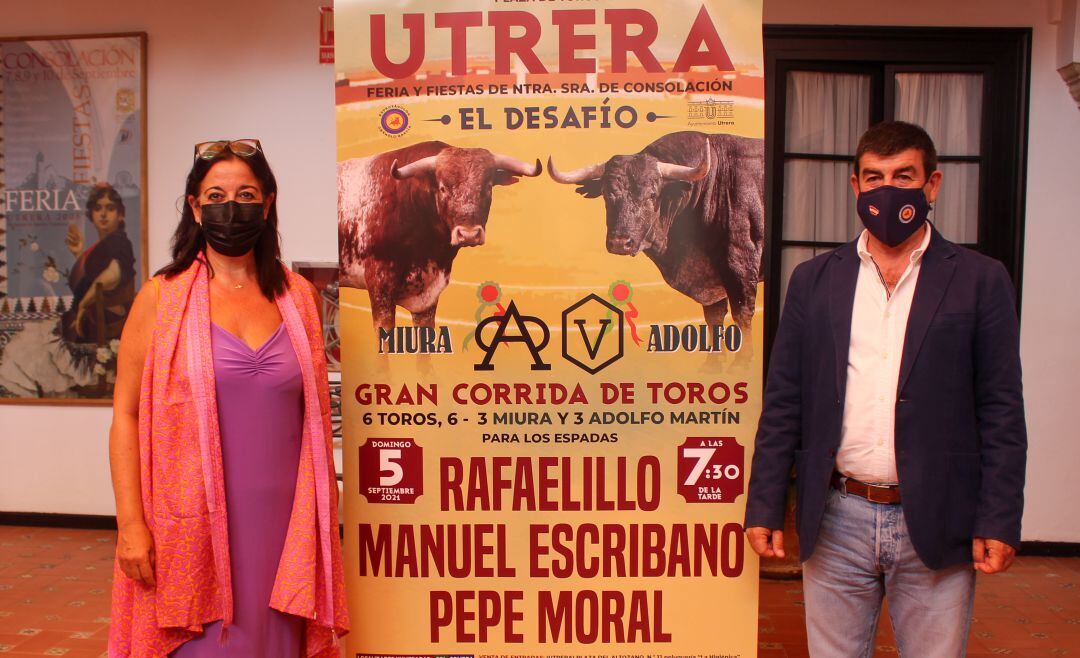 La delegada municipal de Fiestas Mayores de Utrera, Mª del Carmen Cabra, y el empresario Carmelo García posan junto al cartel del Gran Desafío Ganadero